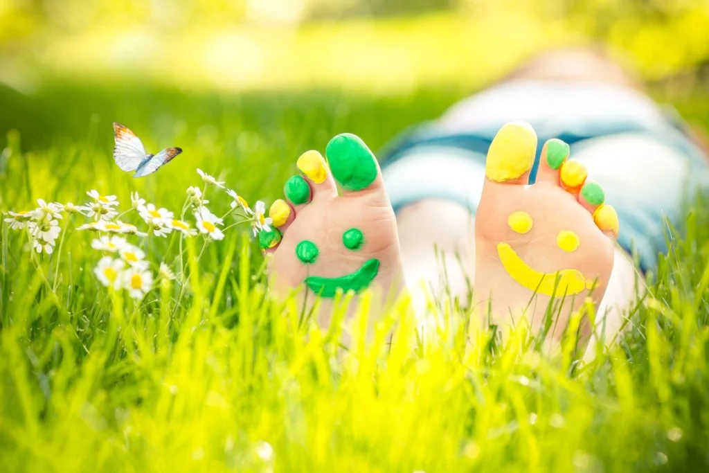Common paediatric foot conditions - child lying down in grass barefoot