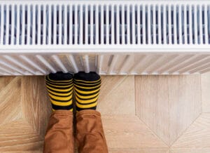 Person with feet against the radiator to avoid cold feet in winter