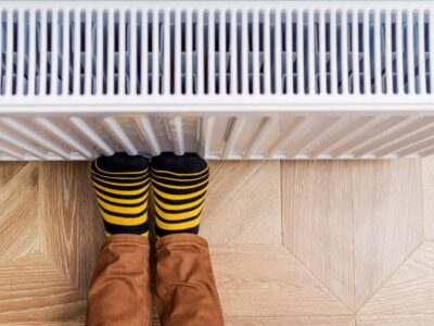 Person with feet against the radiator to avoid cold feet in winter