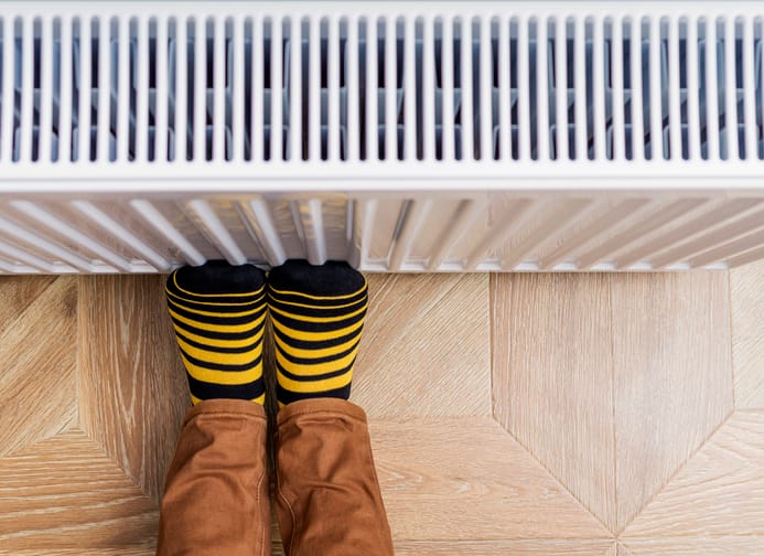 Person with feet against the radiator to avoid cold feet in winter