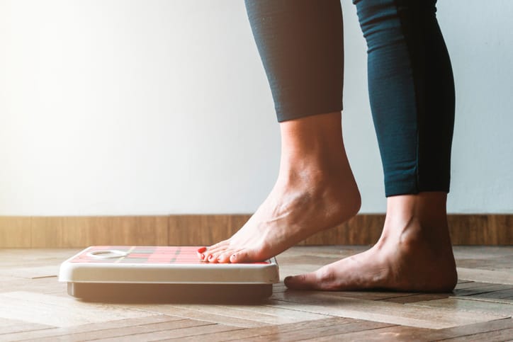 Person weighing themselves as they aim to shed some christmas pounds