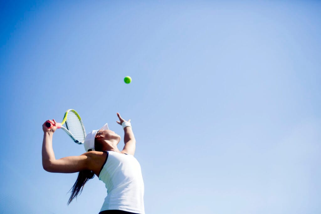 Summer injury prevention tips - a young woman playing tennis