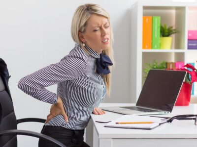 Woman with lower back pain in office chair