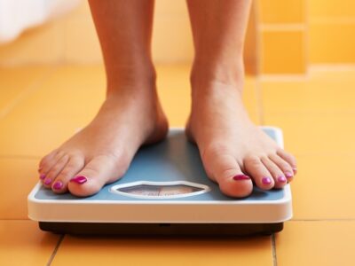 View of womans feet standing on weight scales