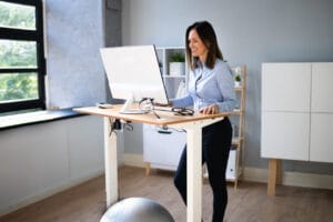 Workplace posture and ergonomics - female using standing desk for her posture