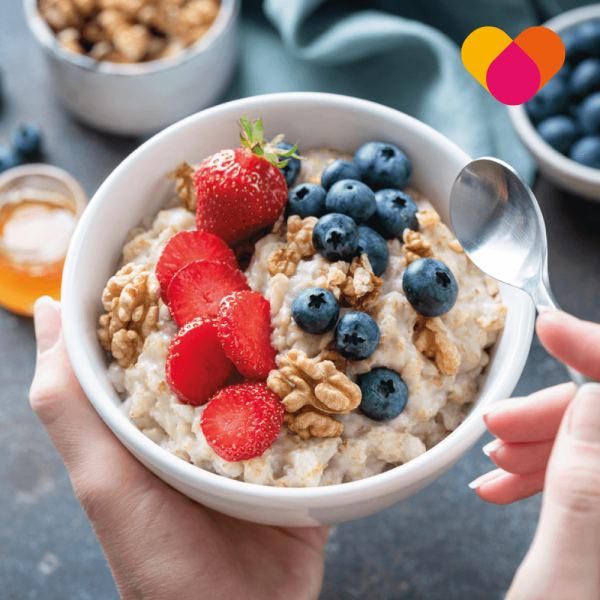 Woman eating a bowl of porridge with fruits and cereals