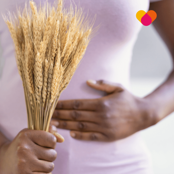 Wheat-Intolerance Woman holding wheat in her hand and other hand on stomach, signifying wheat intolerance